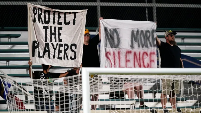 Fans hold signs in support of the players during an NWSL soccer match between the North Carolina Courage and Racing Louisville FC on Wednesday. 