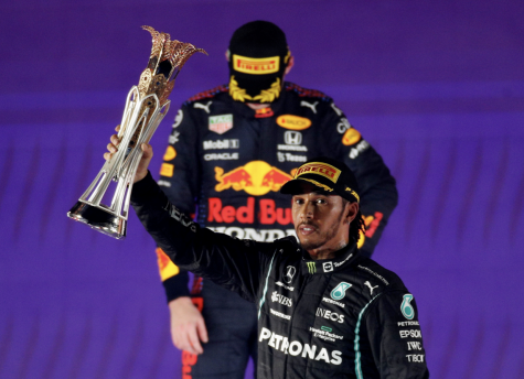 Mercedes Lewis Hamilton celebrates with the trophy on the podium after winning the race as second placed Red Bulls Max Verstappen looks dispirited.