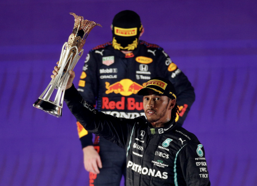 Mercedes' Lewis Hamilton celebrates with the trophy on the podium after winning the race as second placed Red Bull's Max Verstappen looks dispirited.